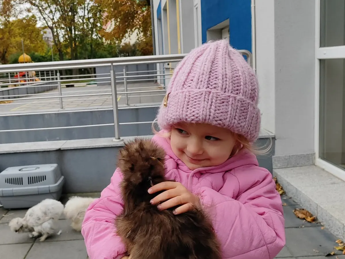 Dziecko z kurą na rękach